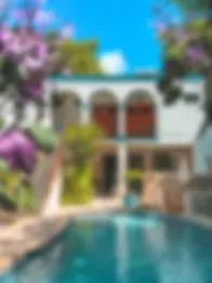 Espacio representativo del hotel: Una piscina frente a un edificio con arcos y árboles en flor.