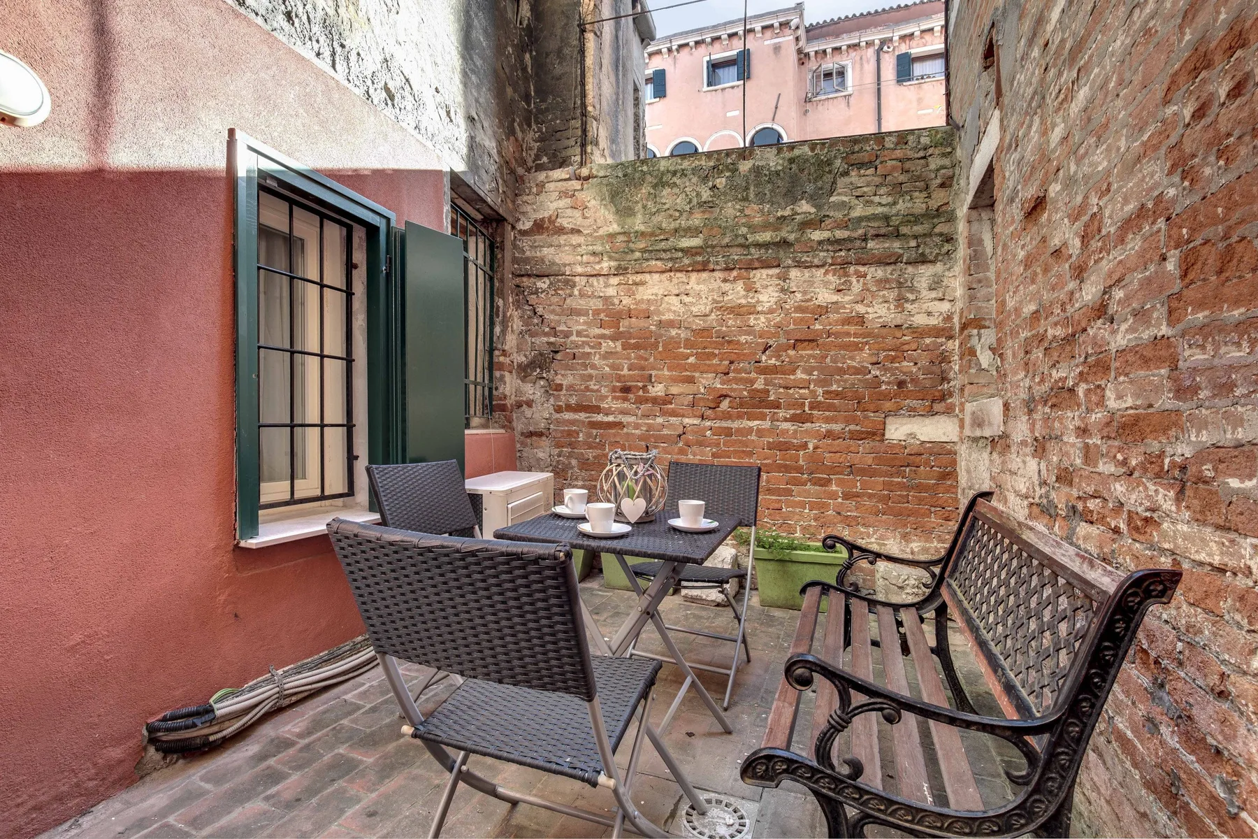 A brick-walled courtyard with outdoor seating and a small table.