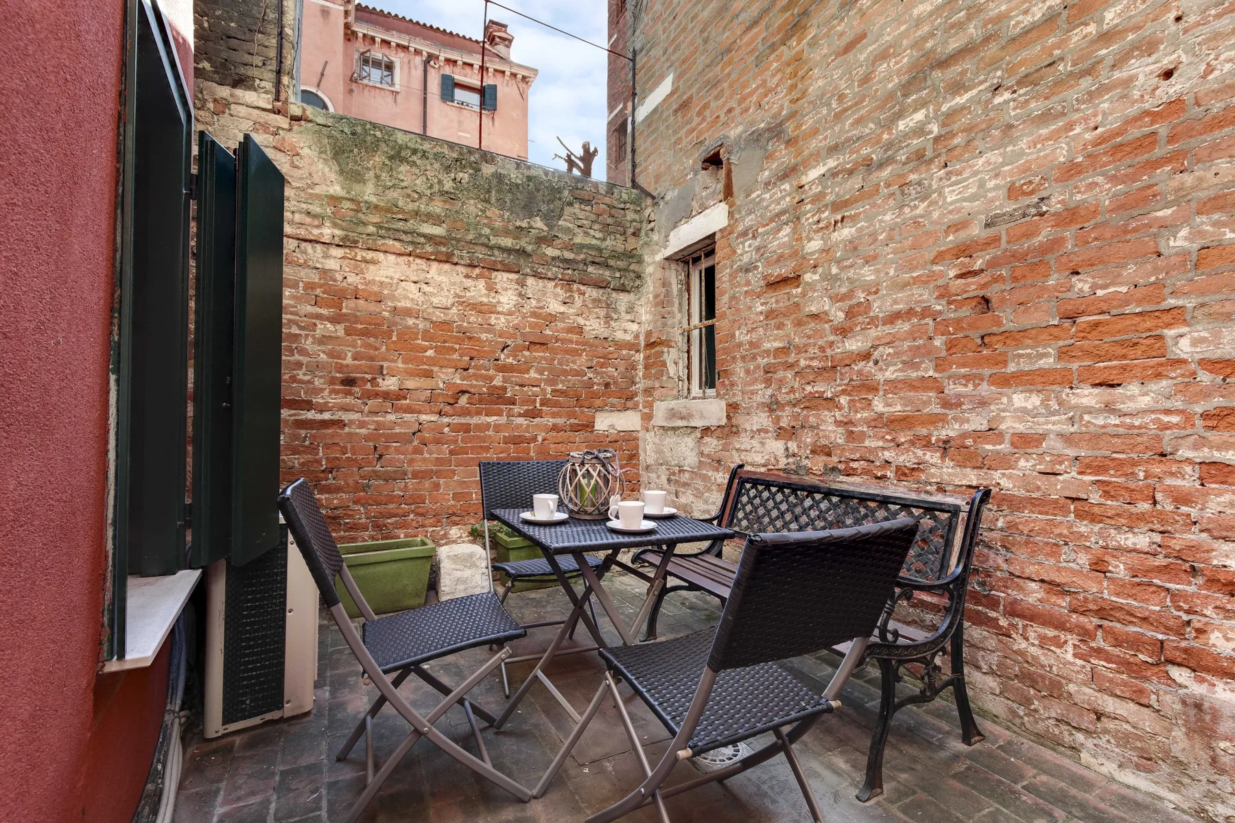 A small brick patio with outdoor seating and a table.