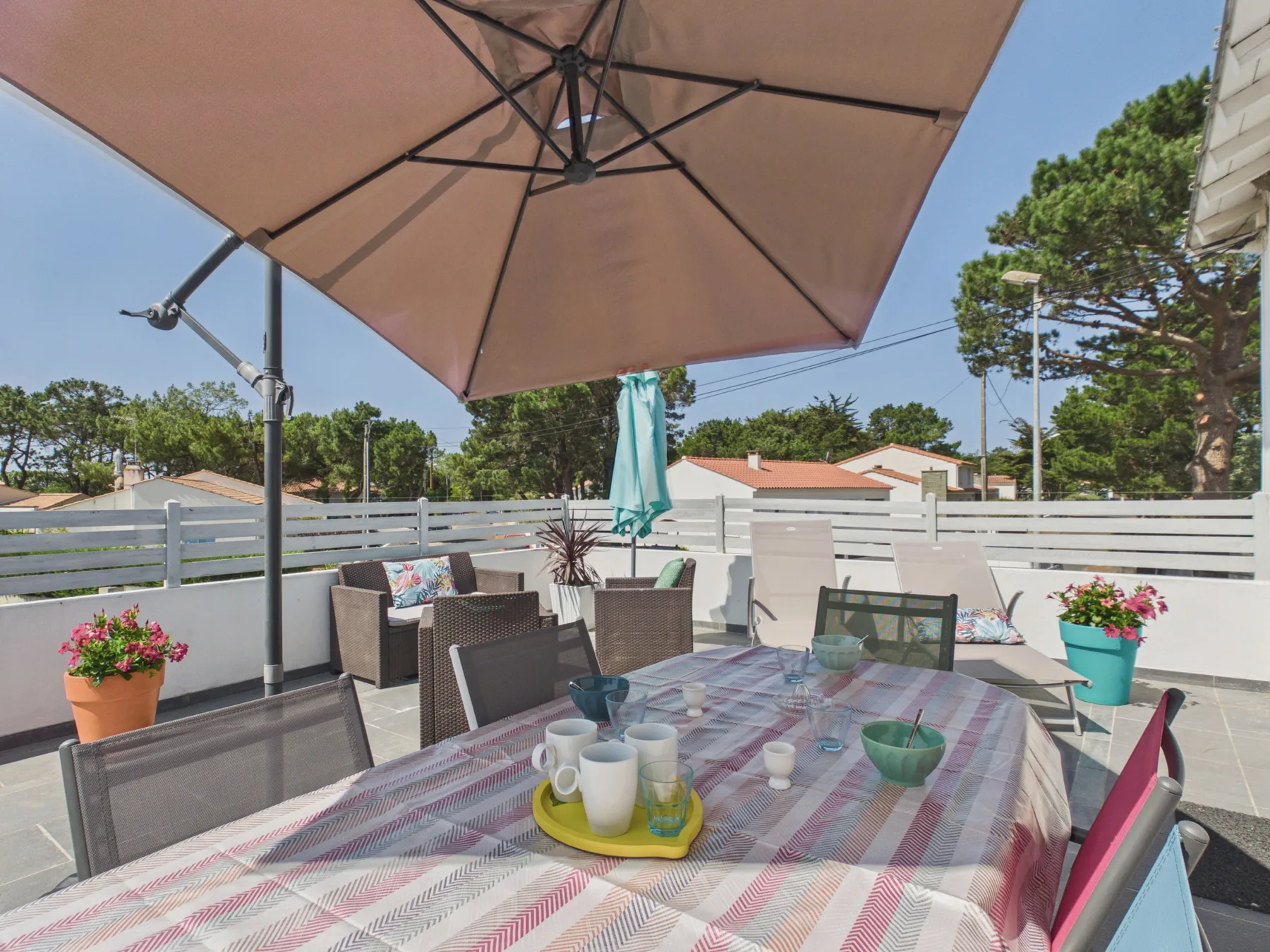 An outdoor dining area with a large umbrella shading a table and seating.