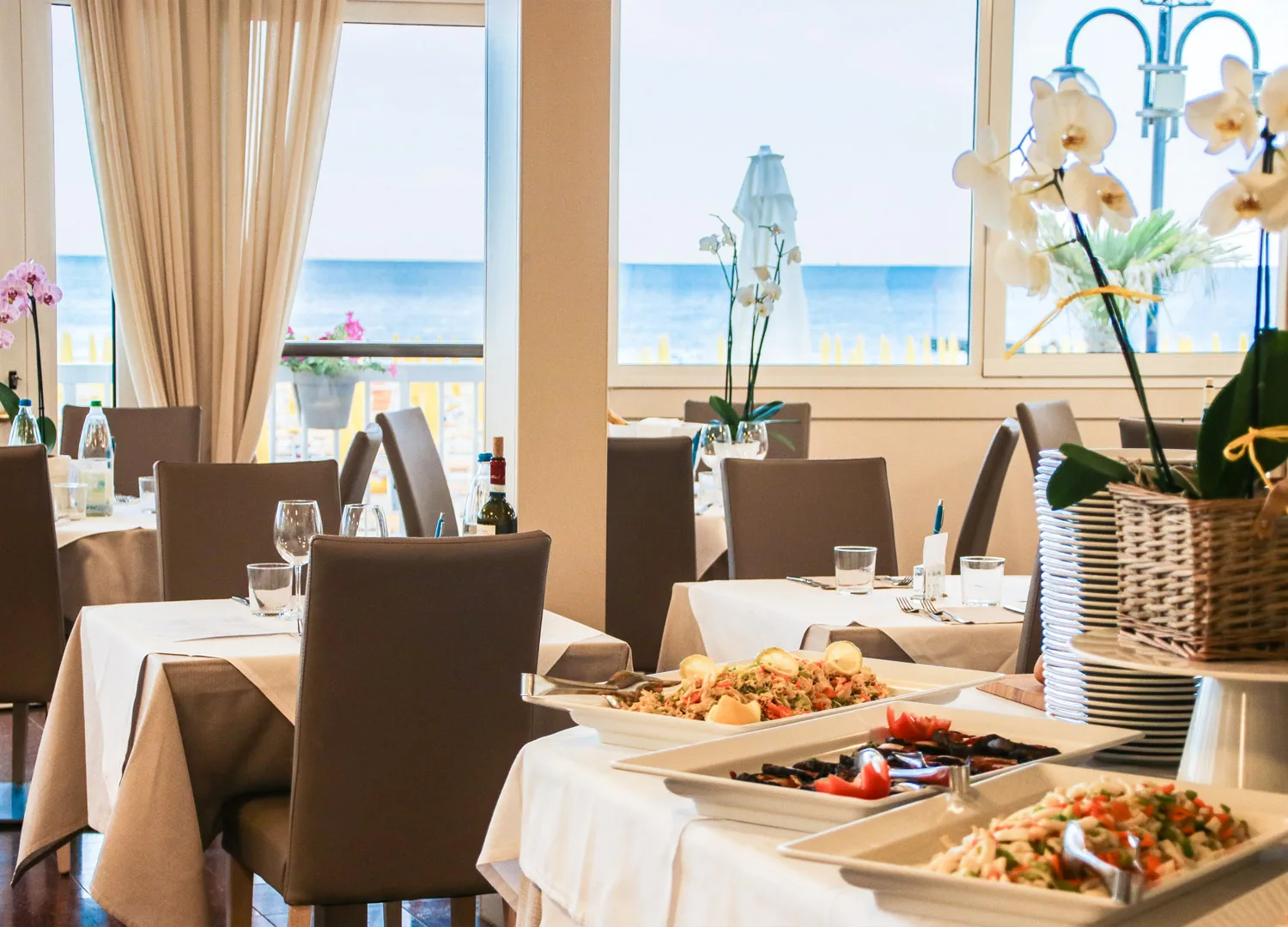 Espacio representativo del hotel: Un comedor con mesas preparadas y platos de bufé junto a grandes ventanas.