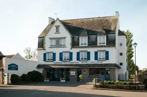 Espacio representativo del hotel: Un edificio hotelero blanco con contraventanas azules da a una zona pavimentada.