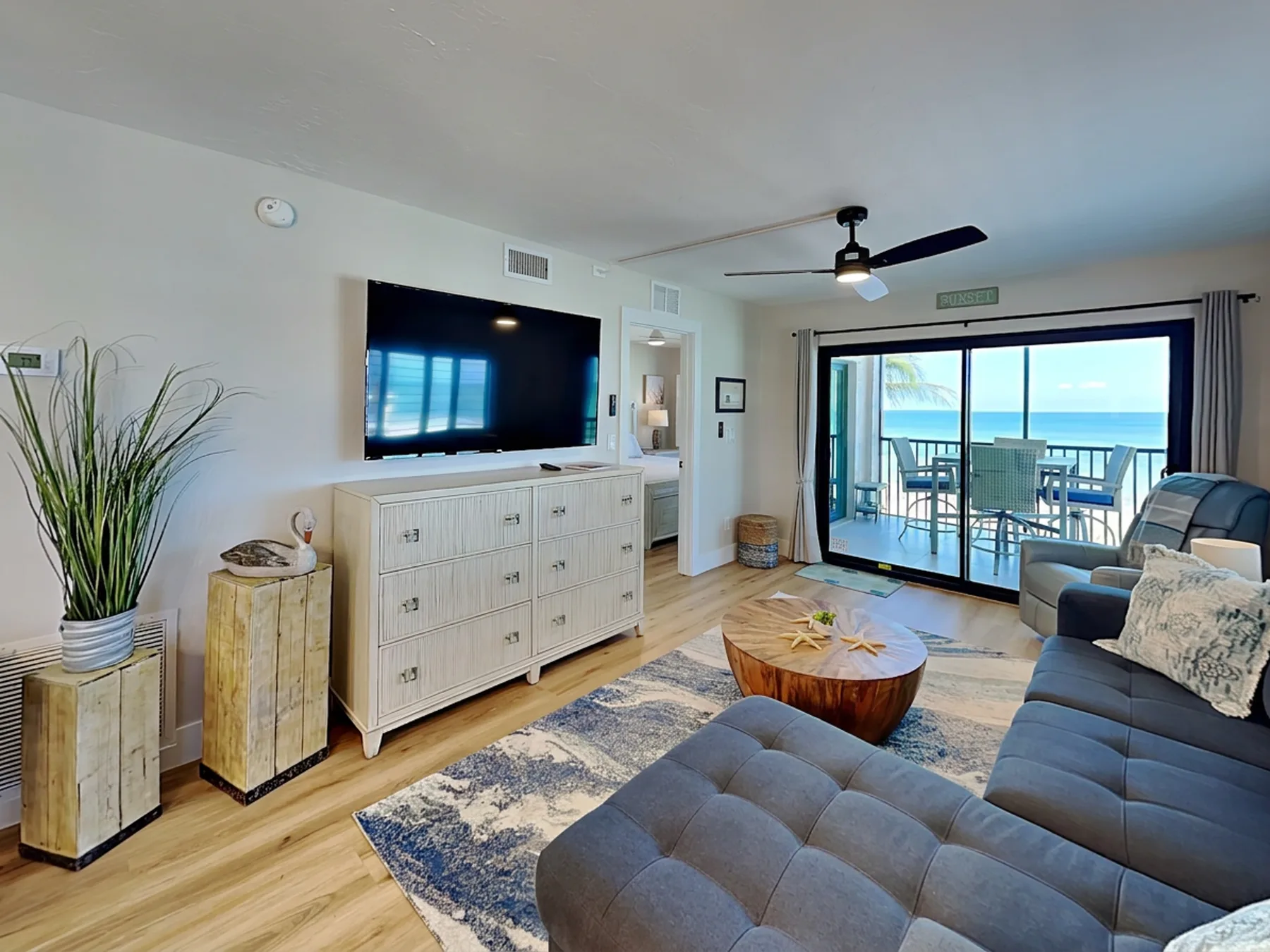 A bright living room opens onto a balcony overlooking the ocean.