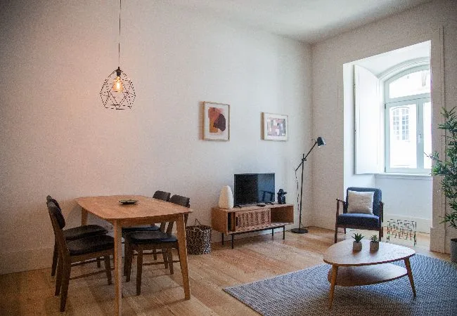Una sala de estar con mesa de comedor, televisor y asientos junto a una ventana luminosa.