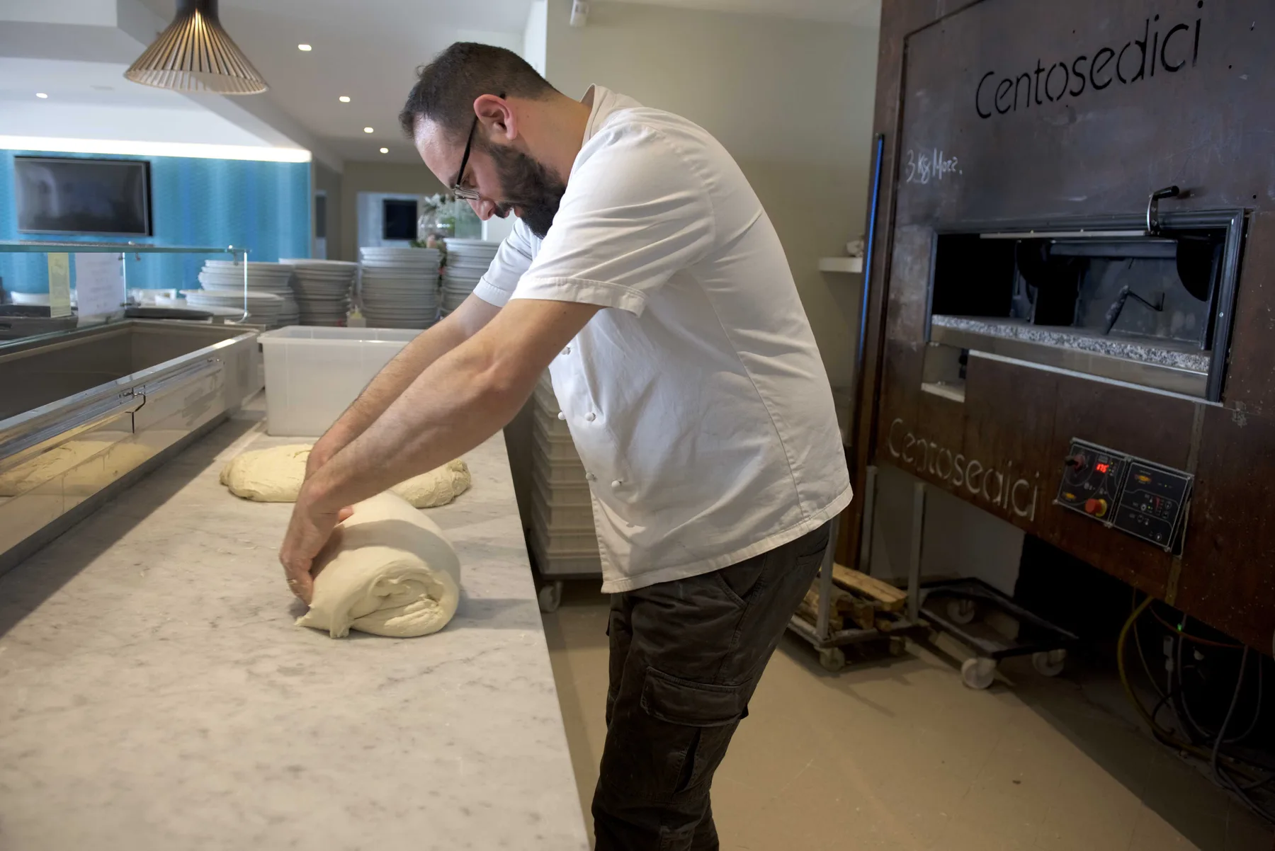 Representative hotel space: A baker shapes dough on a worktable beside a commercial oven.