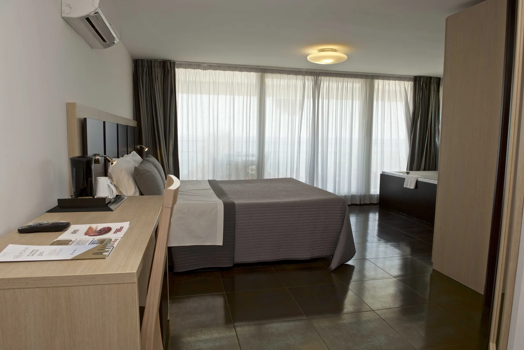Representative hotel space: A hotel bedroom with a bed beside a large curtained window.
