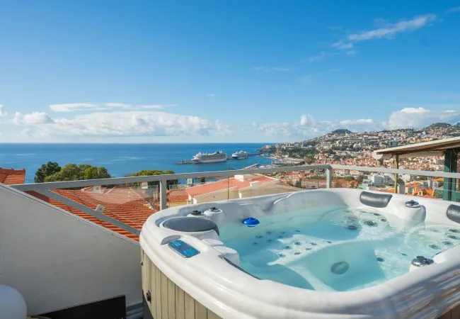 Una bañera de hidromasaje en la azotea ofrece vistas al mar y a un pueblo costero.