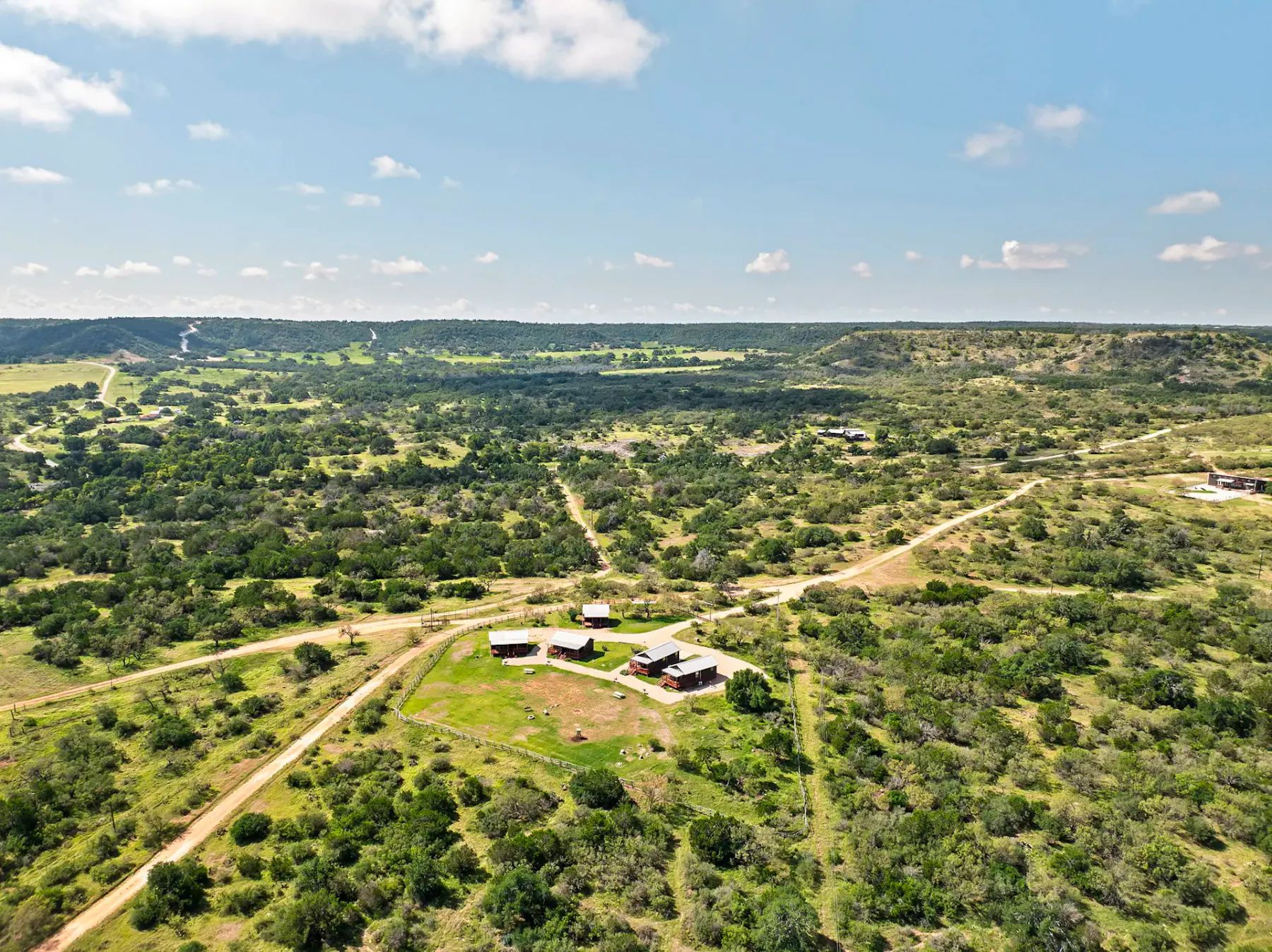 Shared amenity: Aerial view of a rural landscape with a small cluster of buildings and dirt roads.