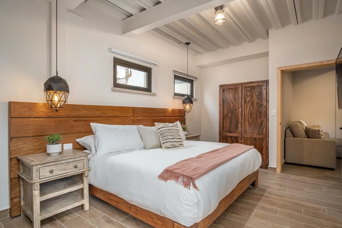 A bedroom with a wooden bed, white bedding, and a plank headboard.