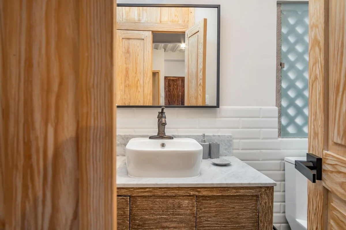 A bathroom vanity with a vessel sink, mirror, and tiled wall.