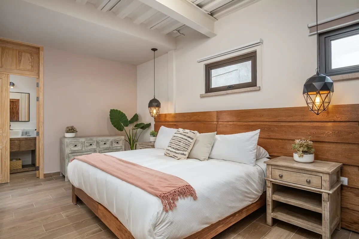 A bedroom with a wooden bed, white bedding, and bedside tables.