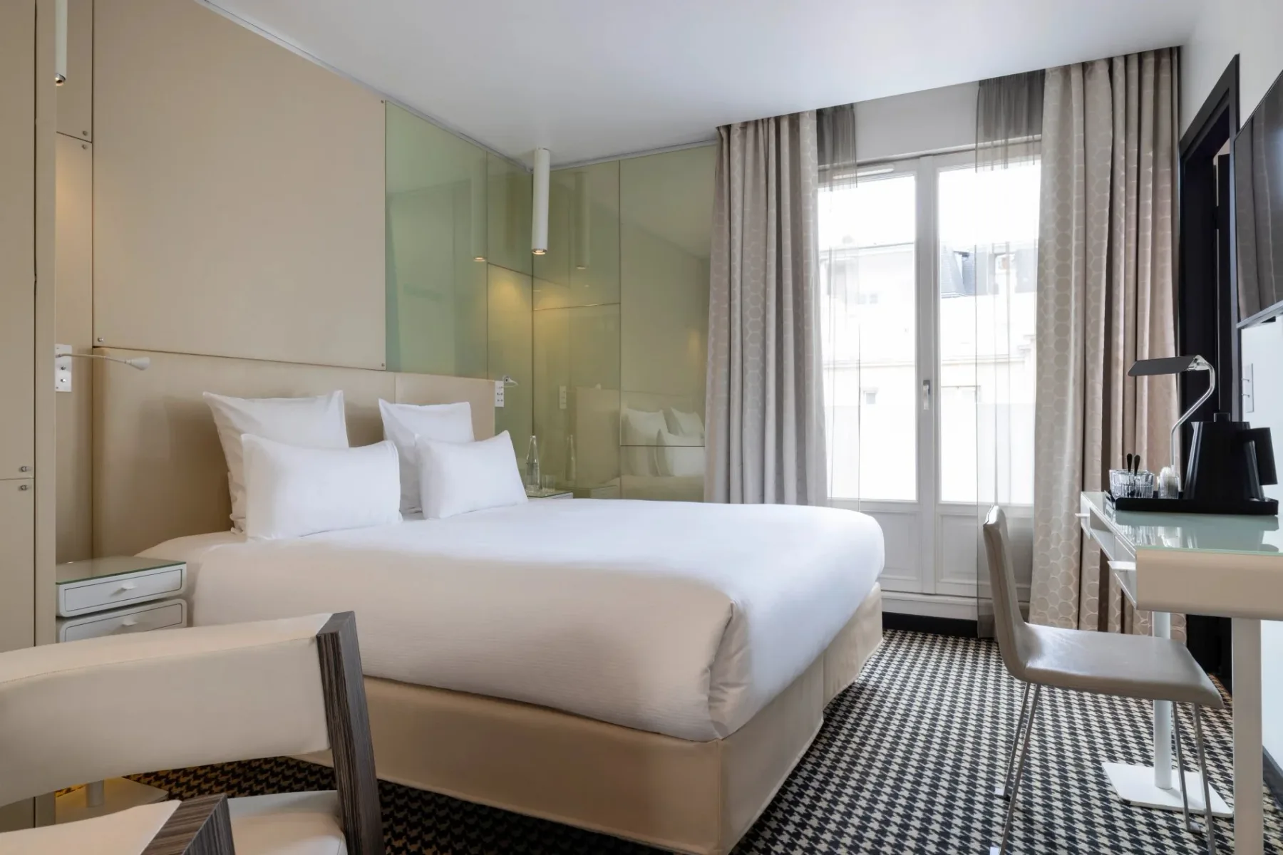 Representative hotel space: A bedroom with a neatly made bed beside a bright window.