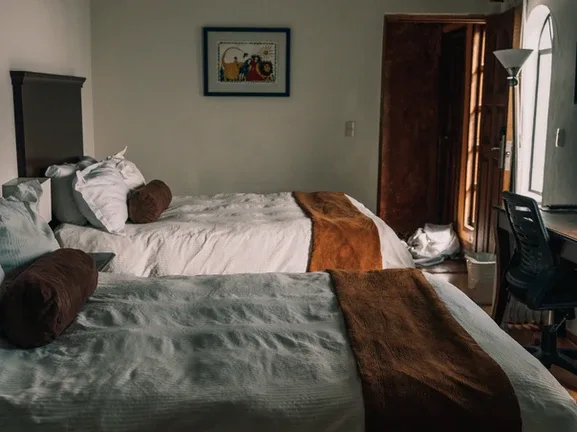 Representative hotel space: A bedroom with two beds, a desk, and a chair beside the window.