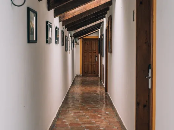 Representative hotel space: A narrow hallway with framed pictures and a wooden door at the end.