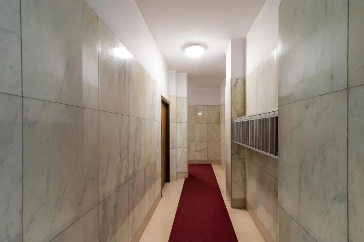 Zona común: Un pasillo con paredes revestidas de azulejos, una alfombra roja y un casillero de correo.
