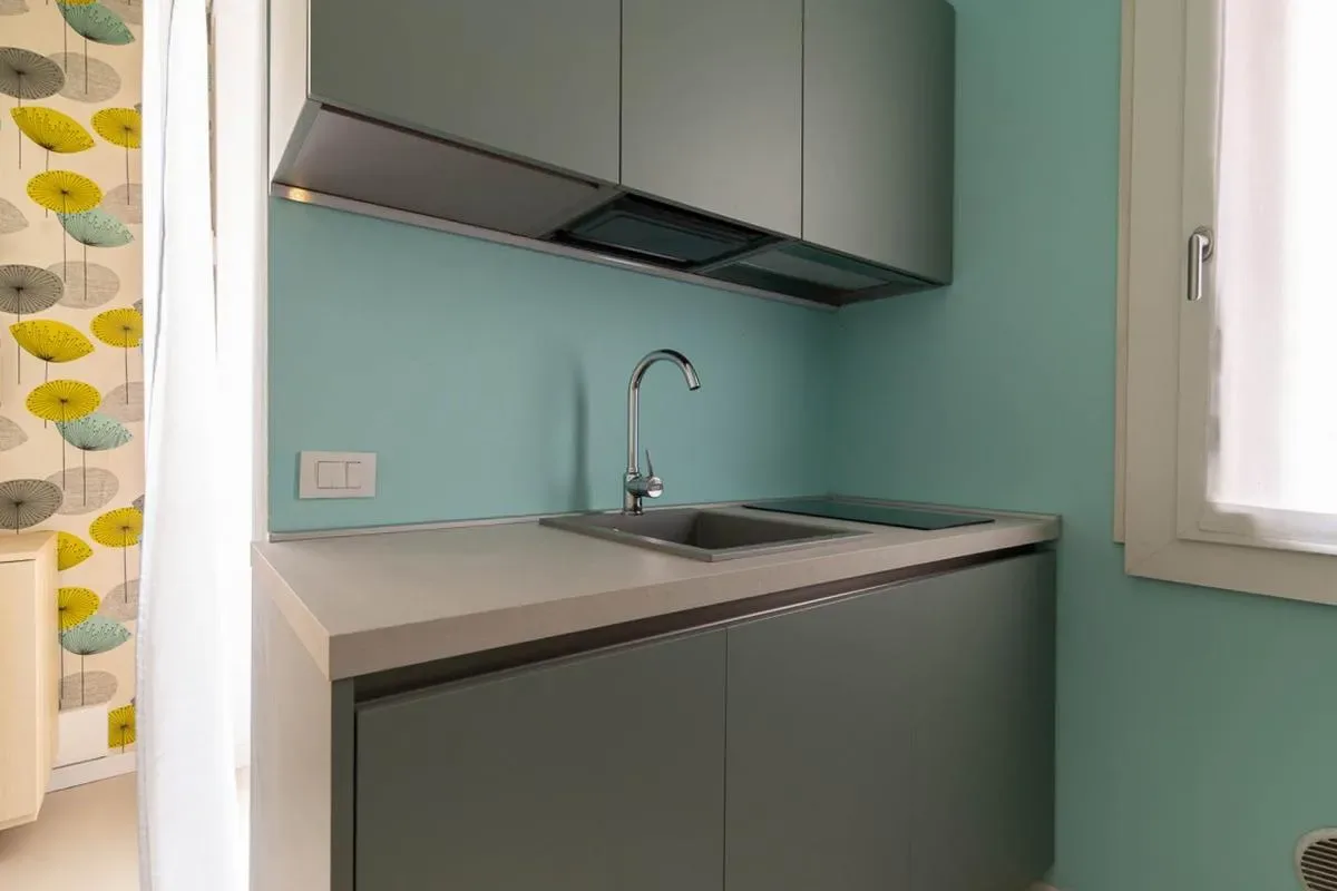 Una pequeña zona de cocina con gabinetes grises, un fregadero y una encimera.