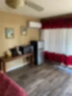Representative hotel space: A sitting area with a desk and a large window with red curtains.