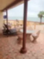 Representative hotel space: A covered outdoor patio overlooks a beach and the water.