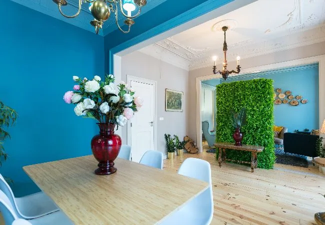Un comedor luminoso con una mesa de madera y un gran arreglo floral.