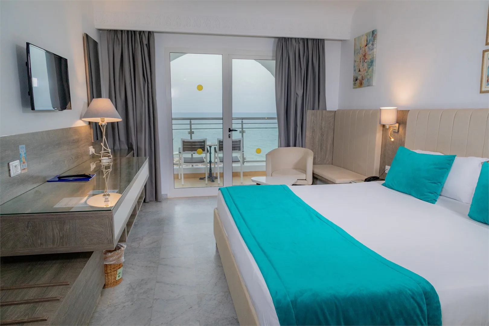 Espacio representativo del hotel: Un dormitorio de hotel con cama, escritorio y puertas de cristal con vistas al mar.