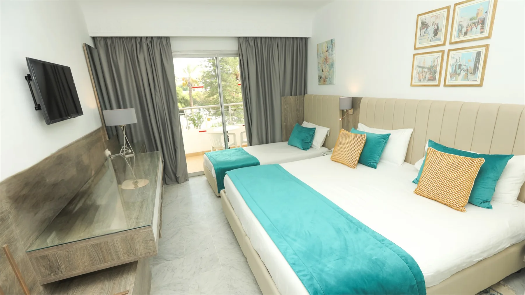 Espacio representativo del hotel: Un dormitorio luminoso con ropa de cama blanca, detalles turquesa y cortinas junto a una ventana.