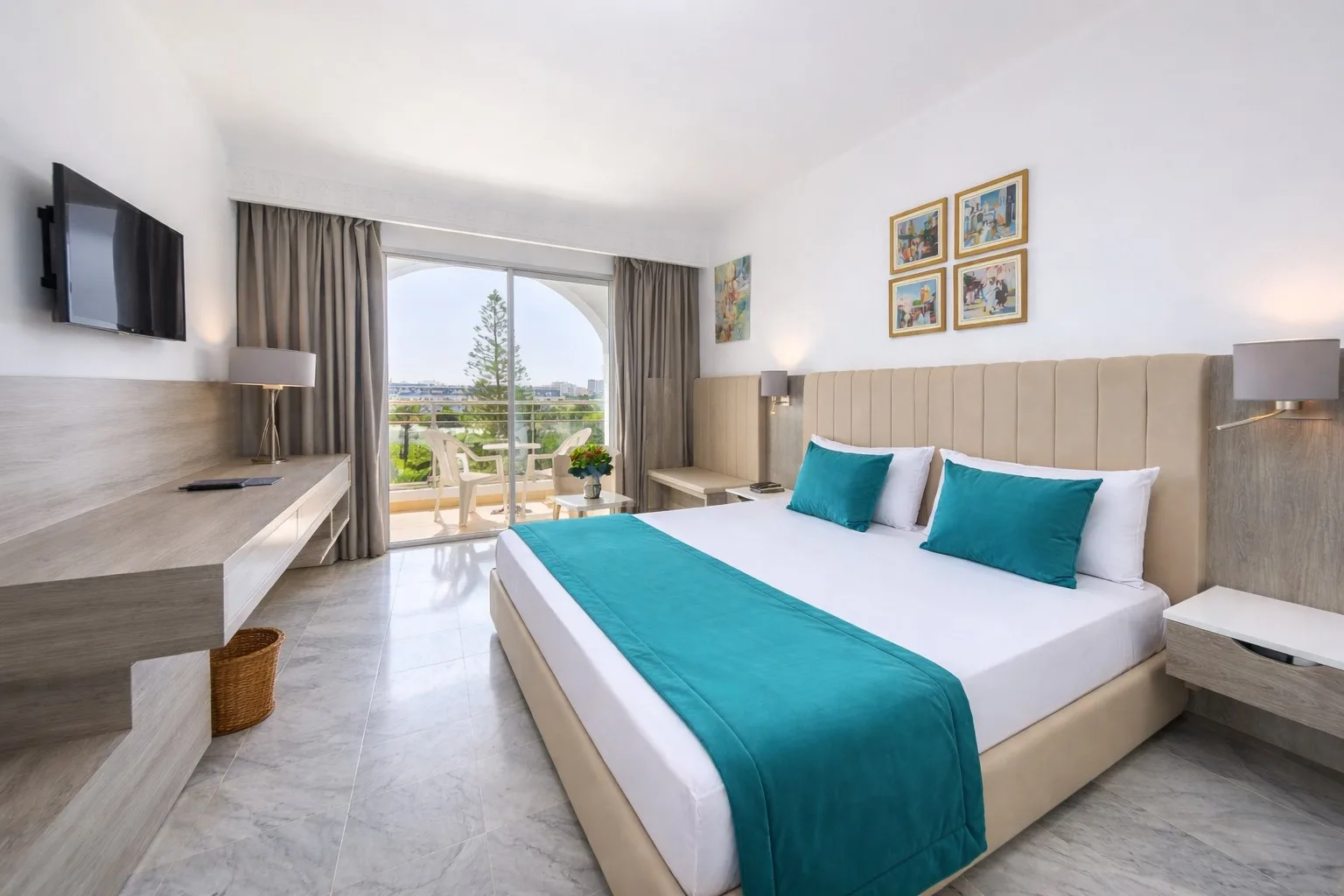 Espacio representativo del hotel: Un dormitorio luminoso con una cama grande, ropa de cama turquesa y vista al balcón.