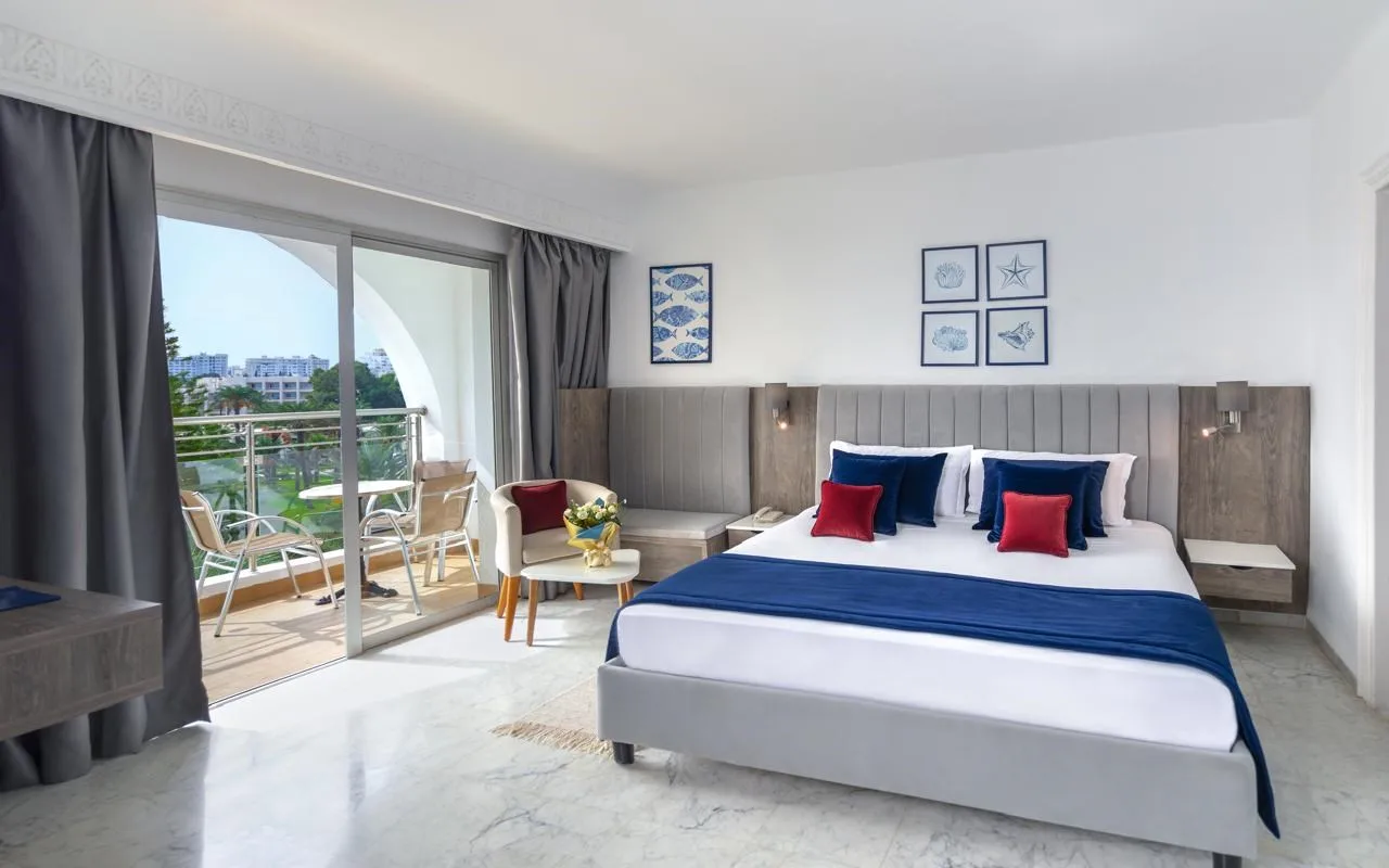 Espacio representativo del hotel: Un dormitorio luminoso con una cama grande y puertas correderas de cristal que dan a un balcón.