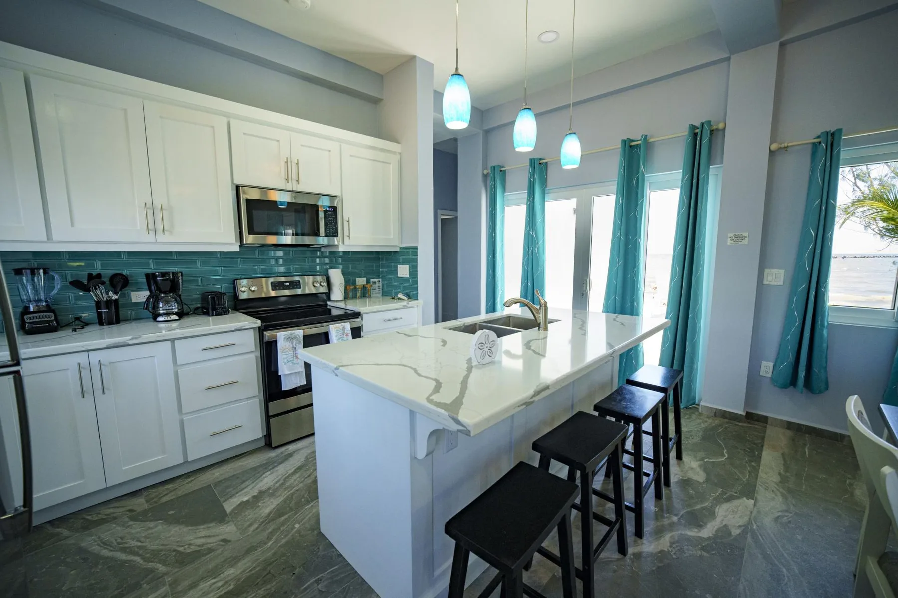 A bright kitchen with white cabinetry, a central island, and pendant lights.