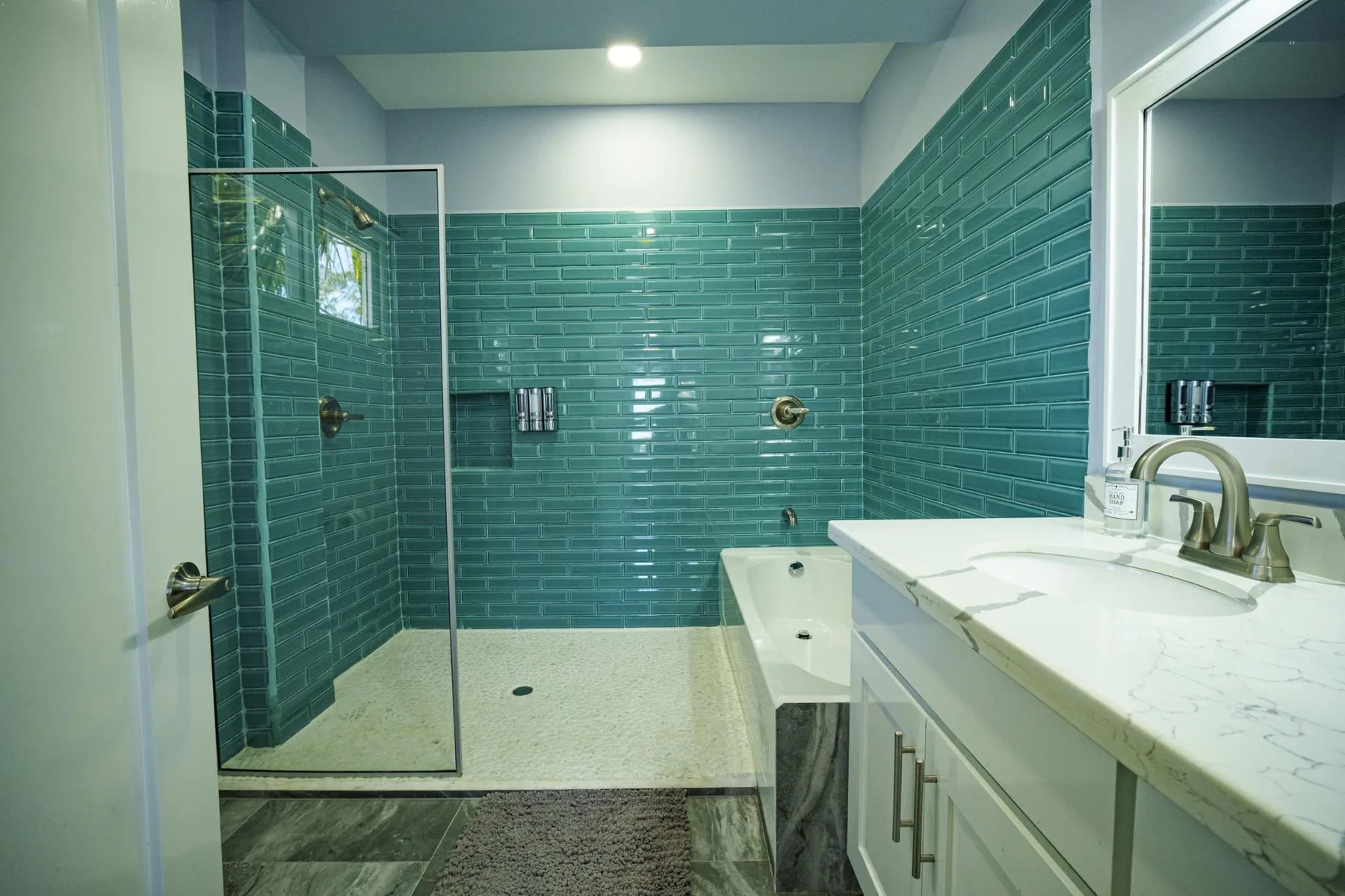 A tiled bathroom with a glass shower and a white vanity.