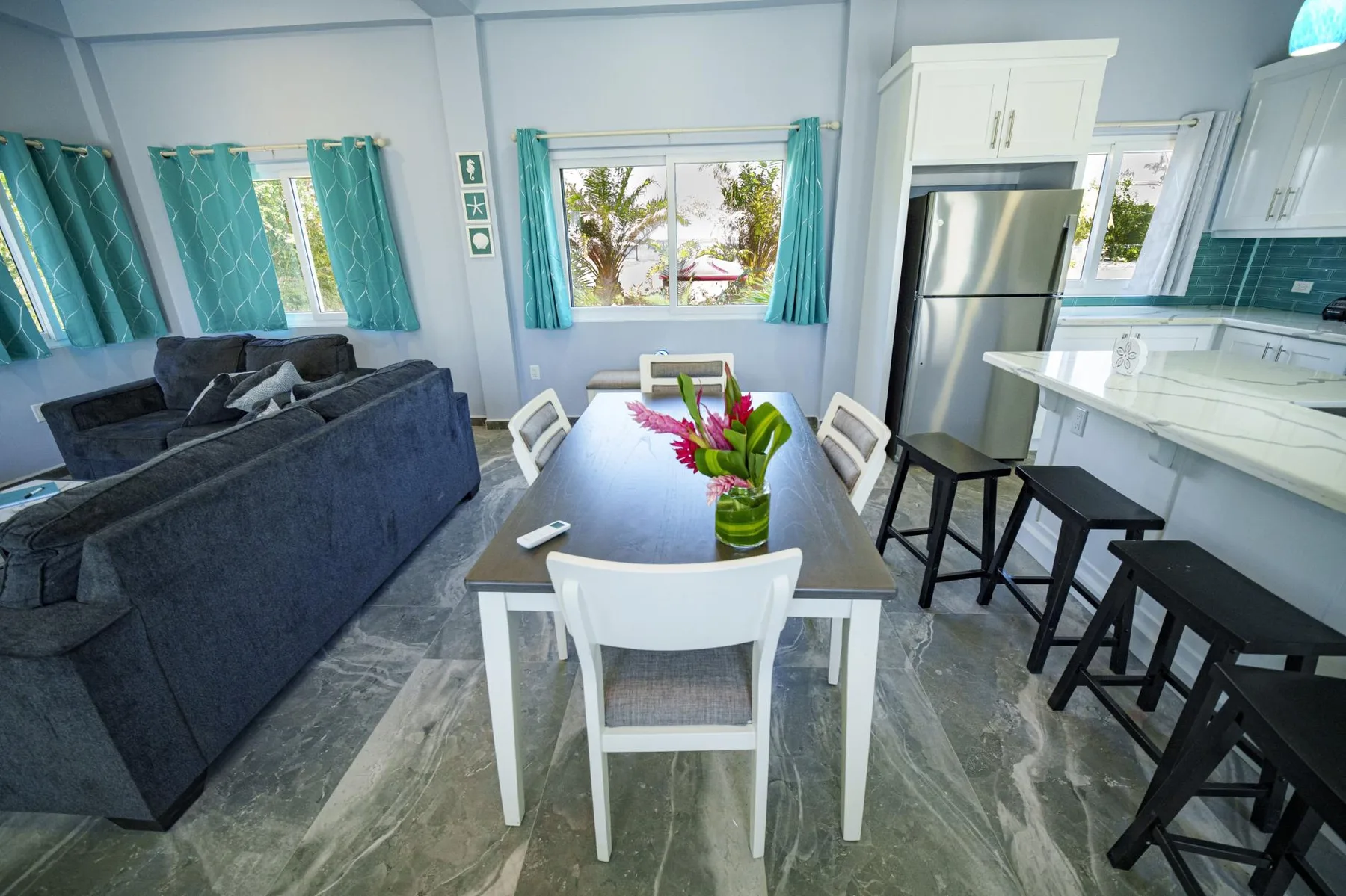 A bright open-plan living and dining area with a kitchen counter and seating.