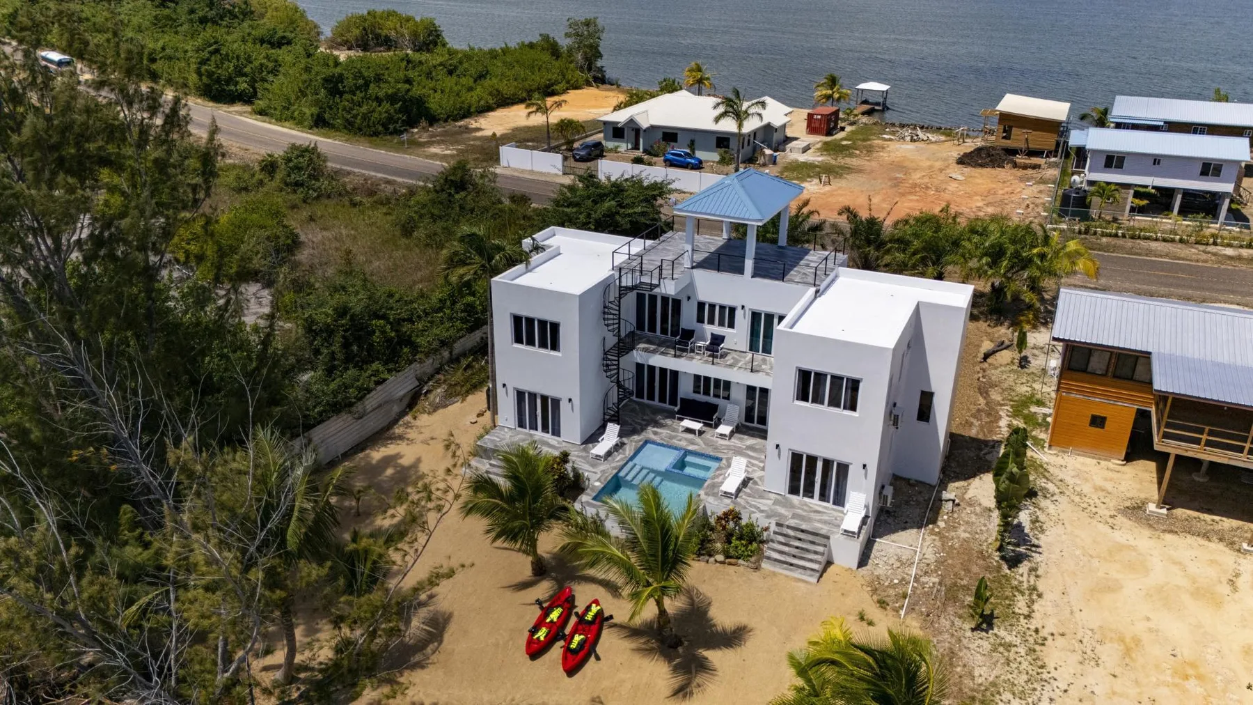 An aerial view shows a modern white building beside a small pool and the shoreline.