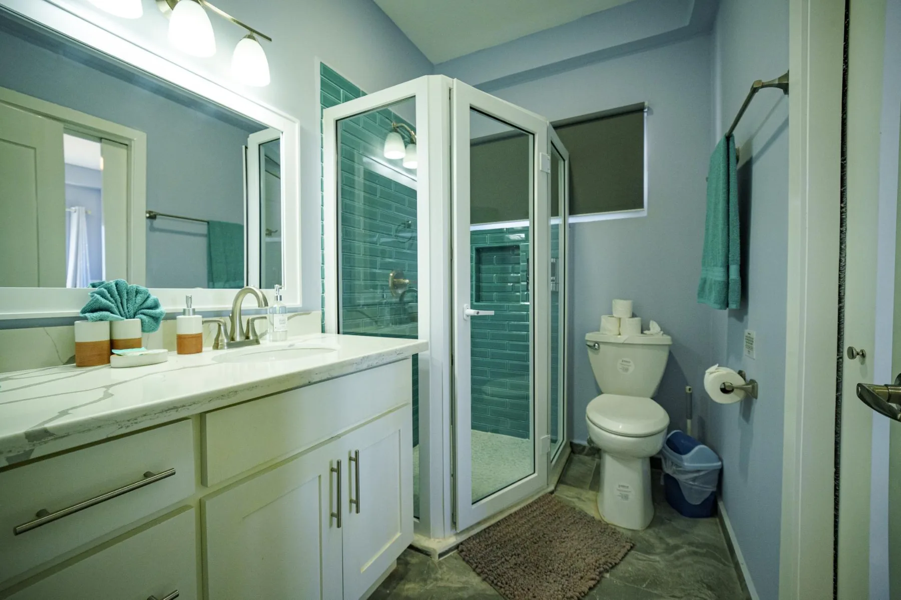 A bathroom with a vanity, mirror, and glass shower.