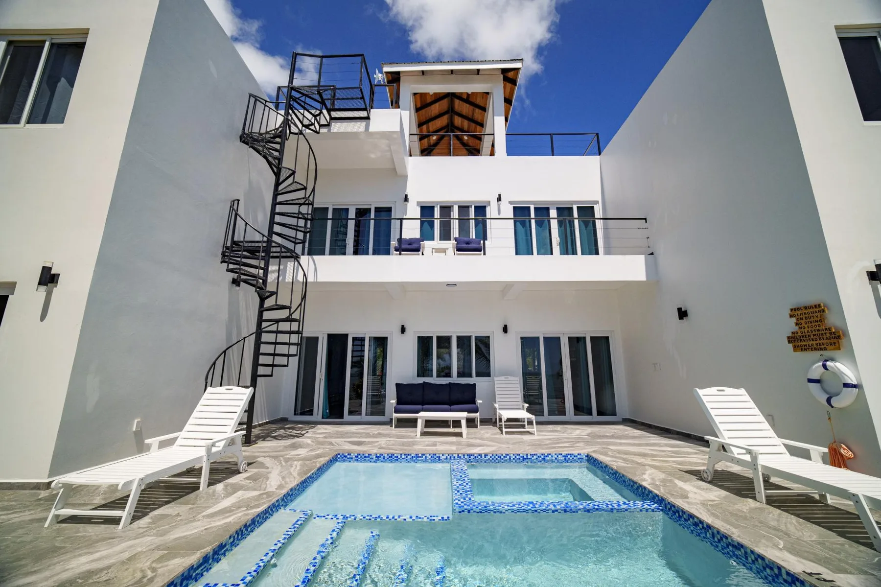 A courtyard pool sits in front of a white multi-level building with balconies.
