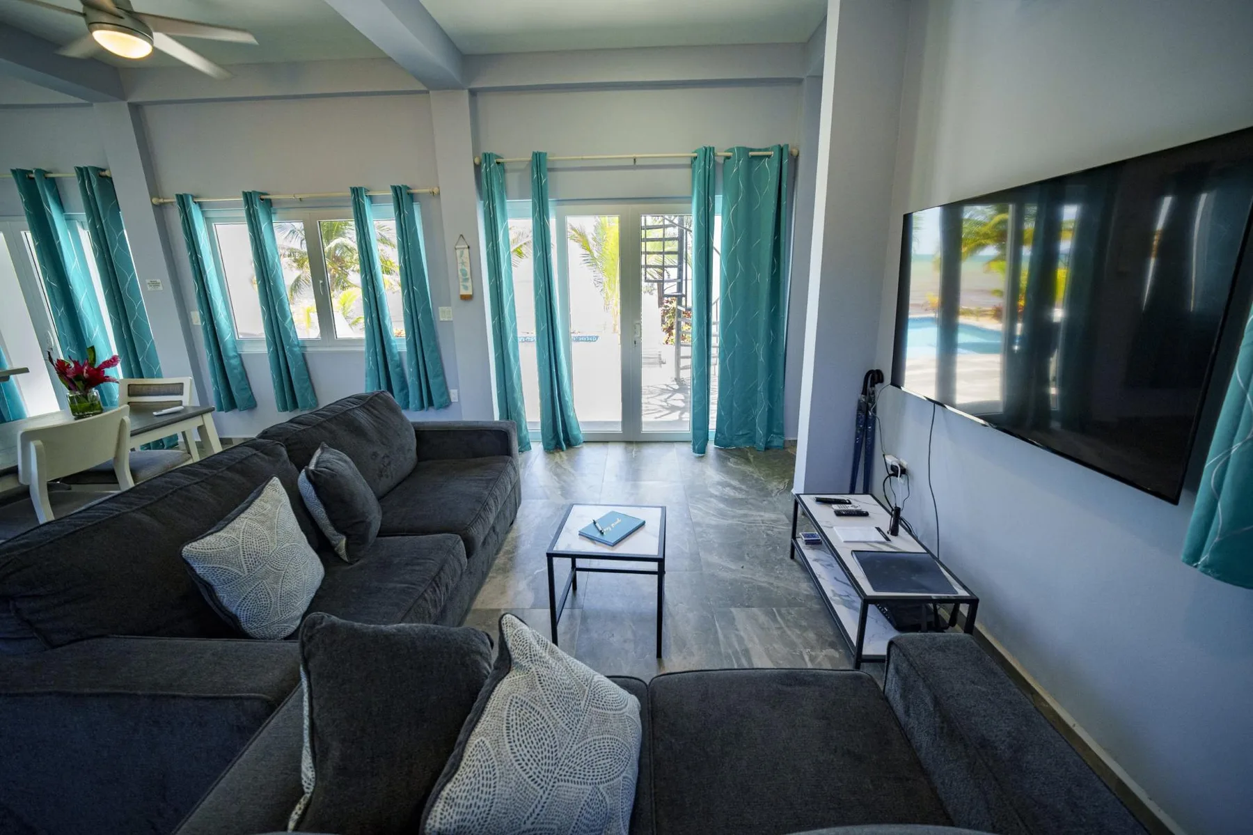 A living room with dark seating, a coffee table, and a wall-mounted television.