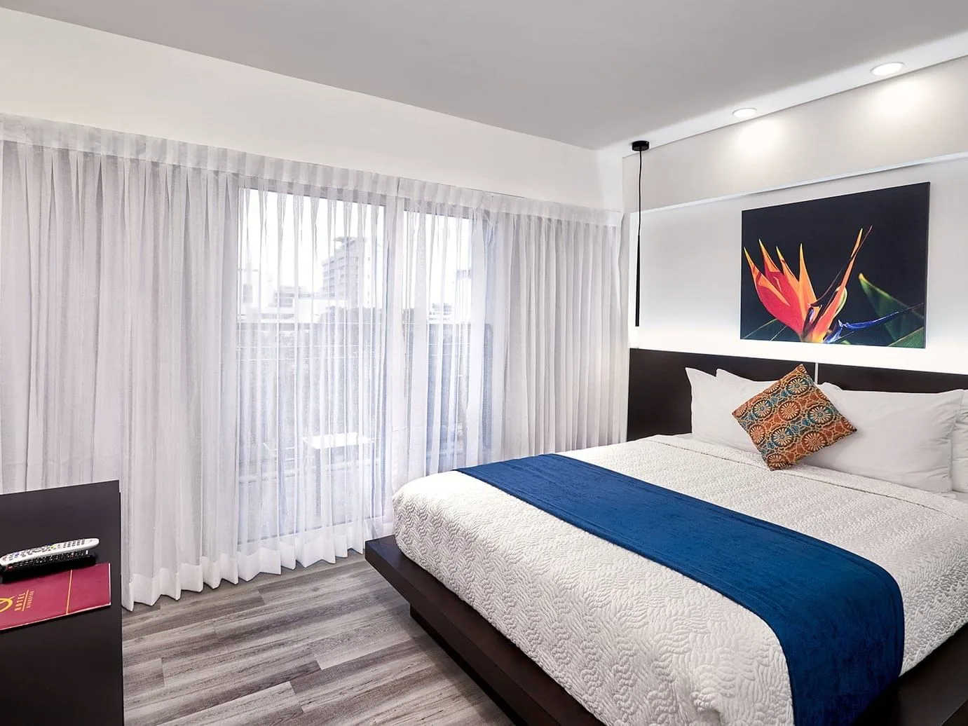 Representative hotel space: A bedroom with a neatly made bed and colorful artwork above the headboard.