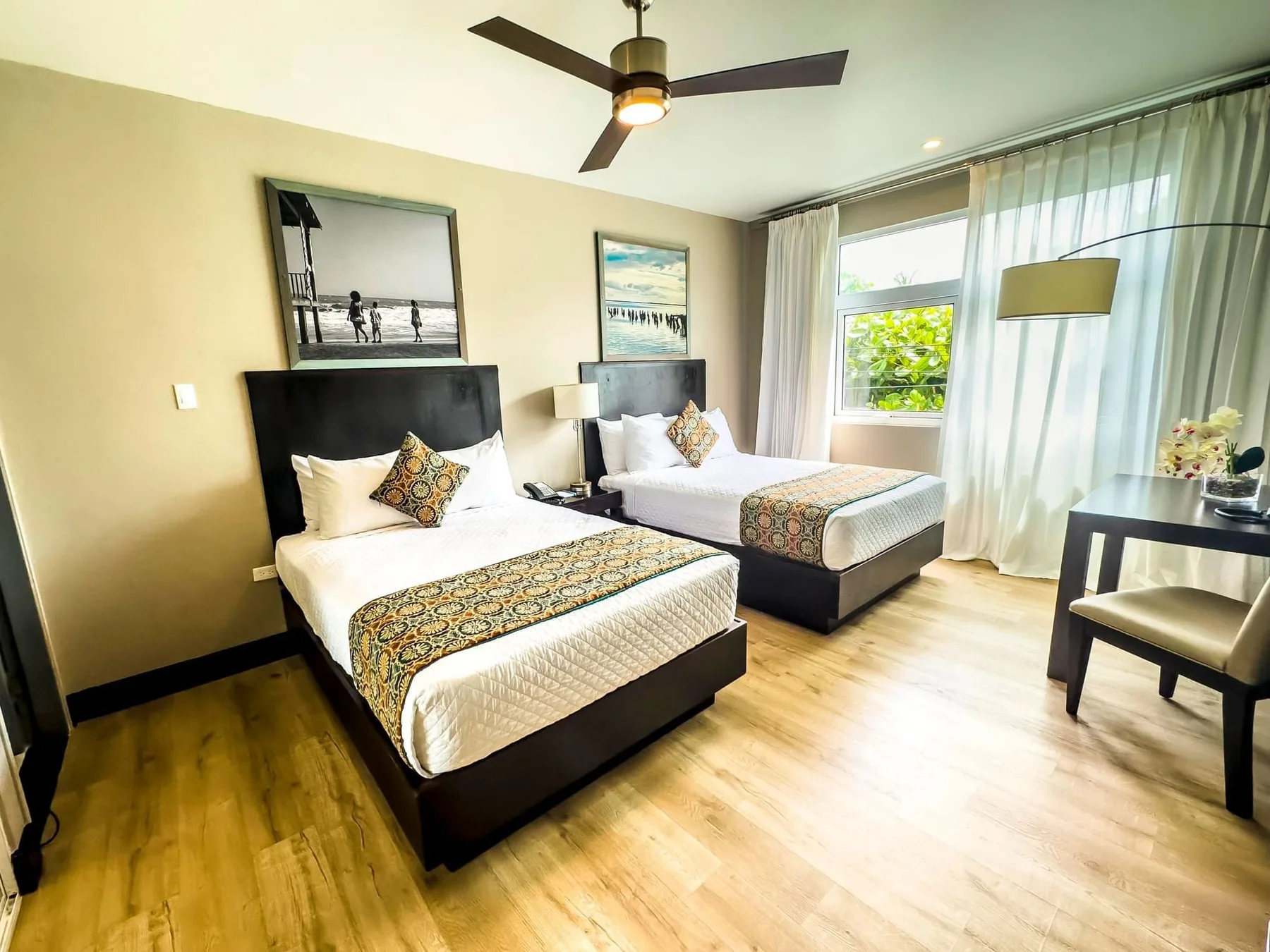 Representative hotel space: A bright bedroom with two beds, large windows, and light curtains.
