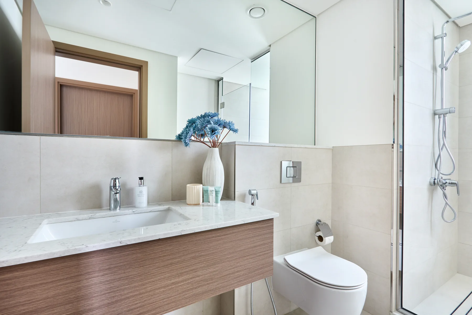 Un baño moderno con un amplio tocador, espejo y ducha.