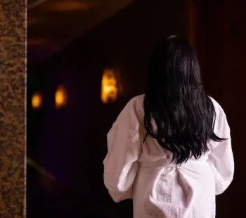 Representative hotel space: A person with long dark hair stands in a dimly lit interior.