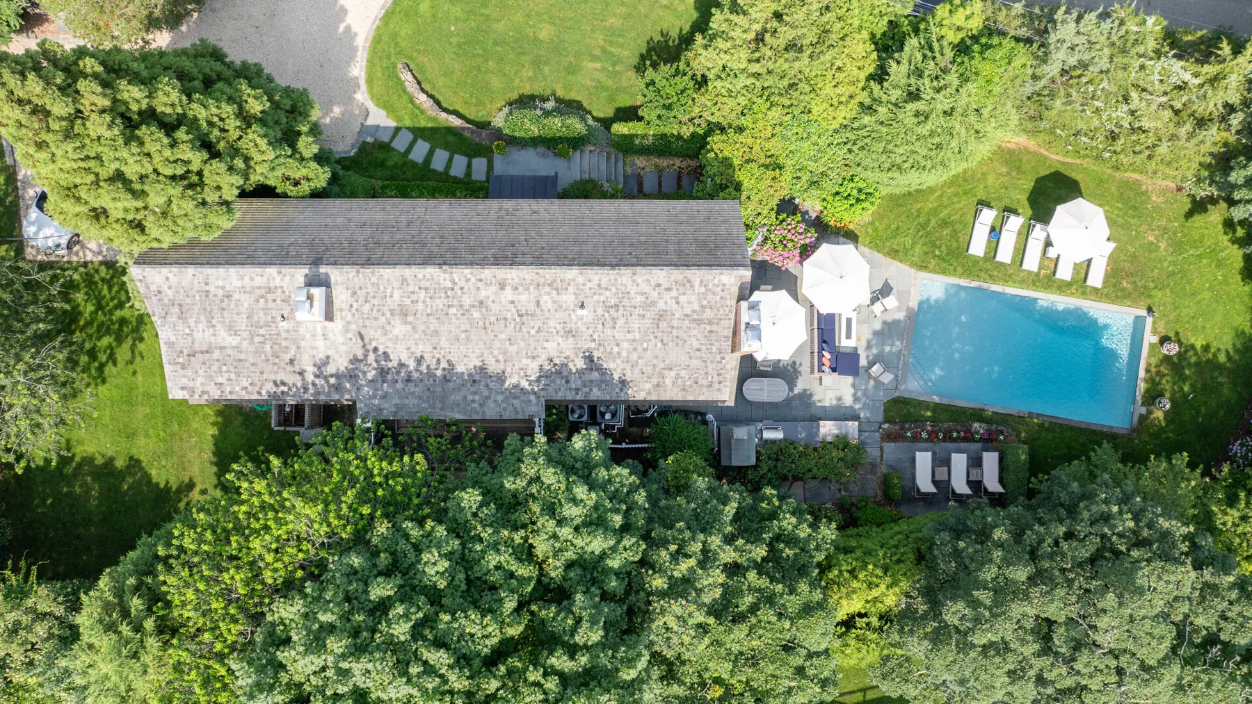 An aerial view of a house, swimming pool, and surrounding green garden.