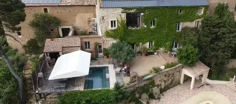 Espacio representativo del hotel: Una piscina exterior junto a un patio de piedra y edificios cubiertos de hiedra.