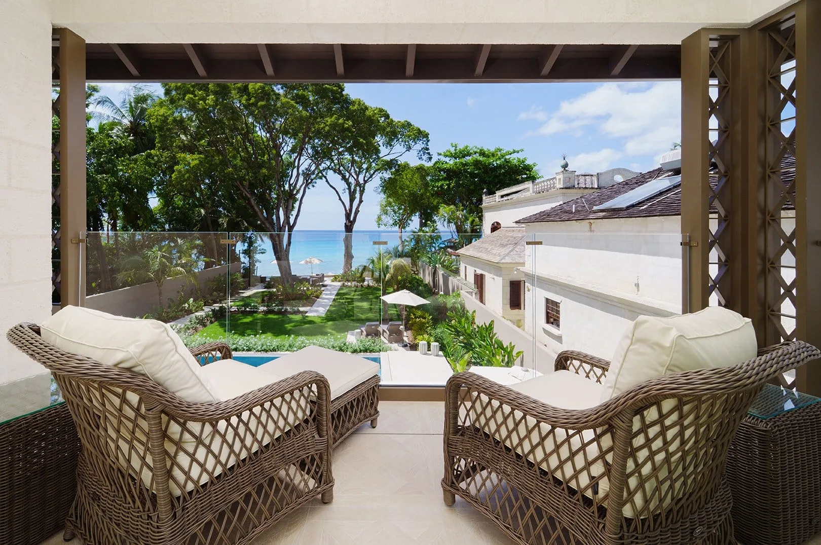 A covered outdoor seating area overlooks a landscaped garden and the ocean.