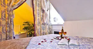 Representative hotel space: A bedroom with a bed, patterned curtains, and a sloped ceiling.