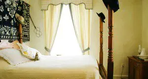 Representative hotel space: A bedroom with a bed beside a bright curtained window.