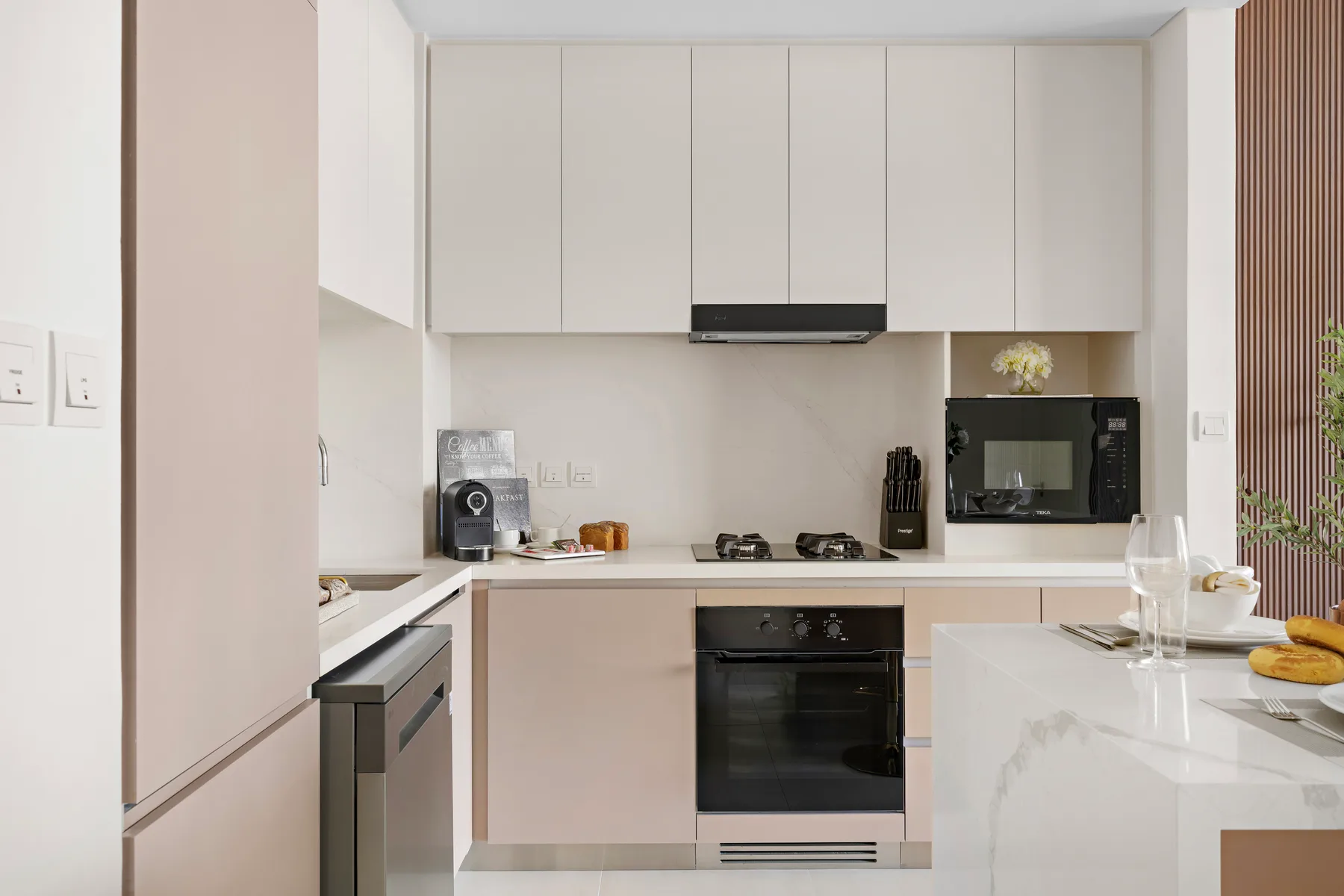 A modern kitchen with pale cabinets, a cooktop, and a central island.