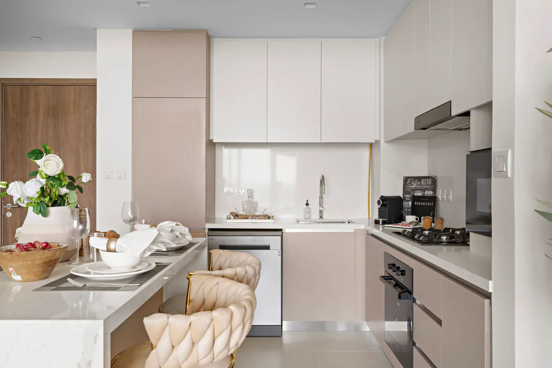 A modern kitchen with white cabinetry, a countertop, and a dining area.