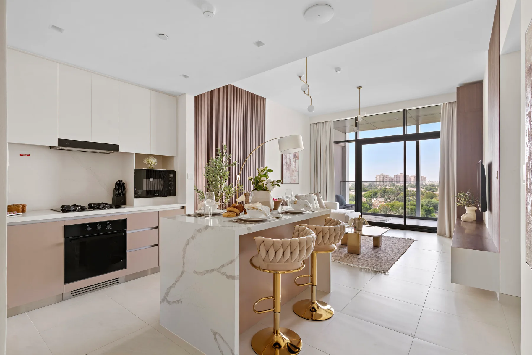 A modern open-plan kitchen and dining area with a marble island and large windows.