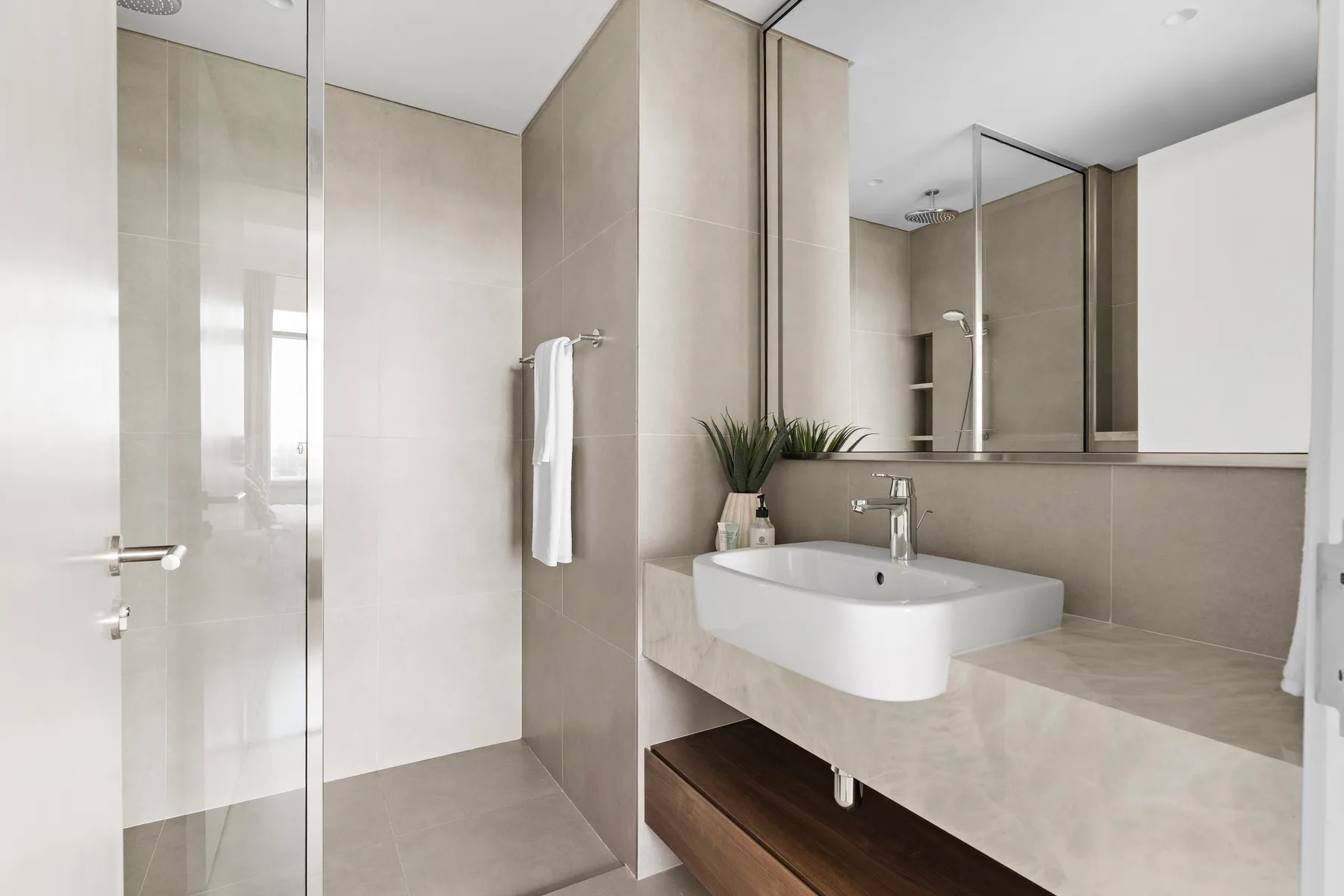 A modern bathroom with a wall-mounted sink and large mirror.