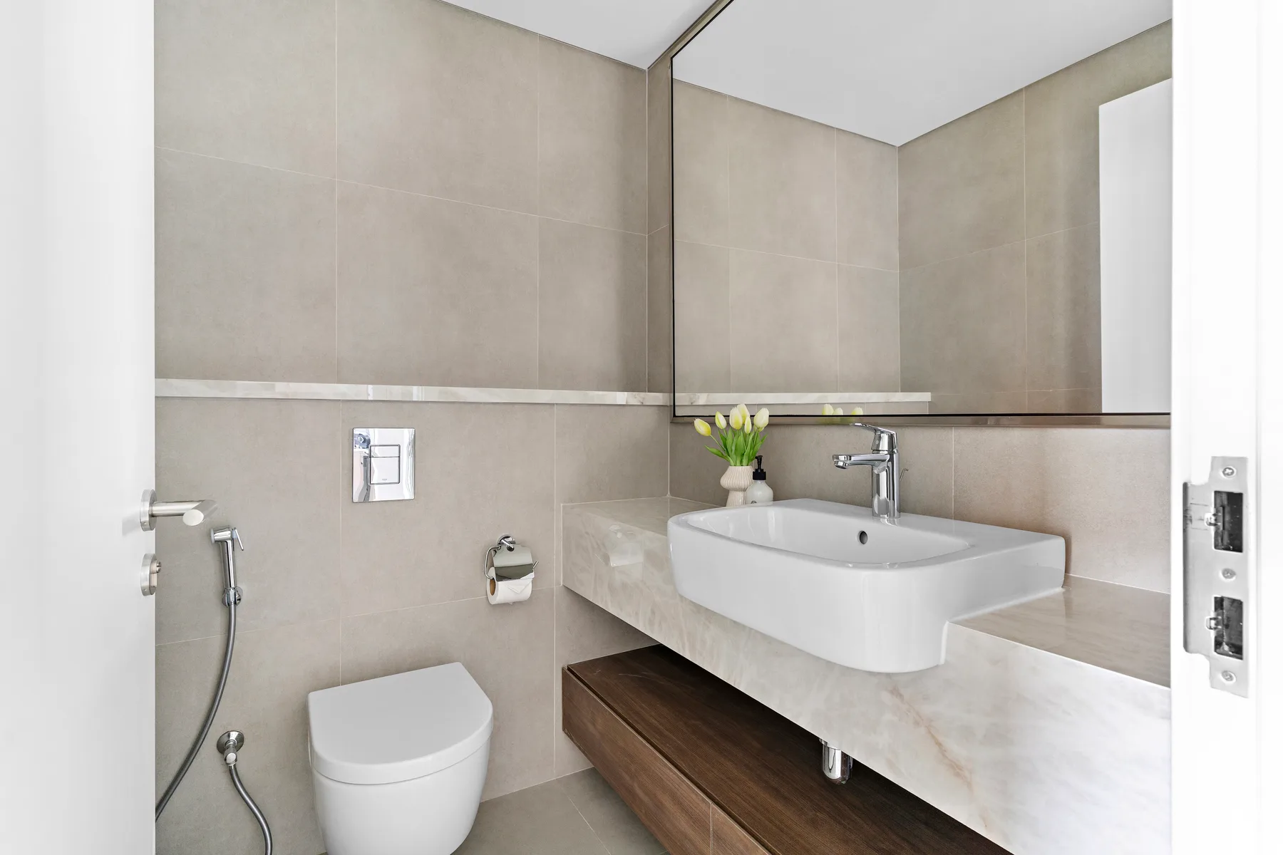 A modern bathroom with a wall-mounted sink and a shower.