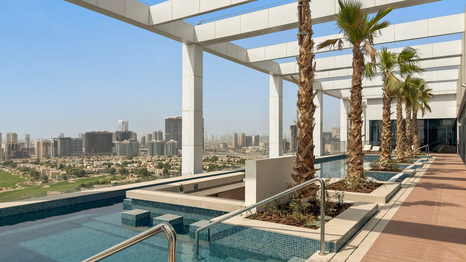 Shared amenity: An outdoor pool terrace with palm trees and a city view.