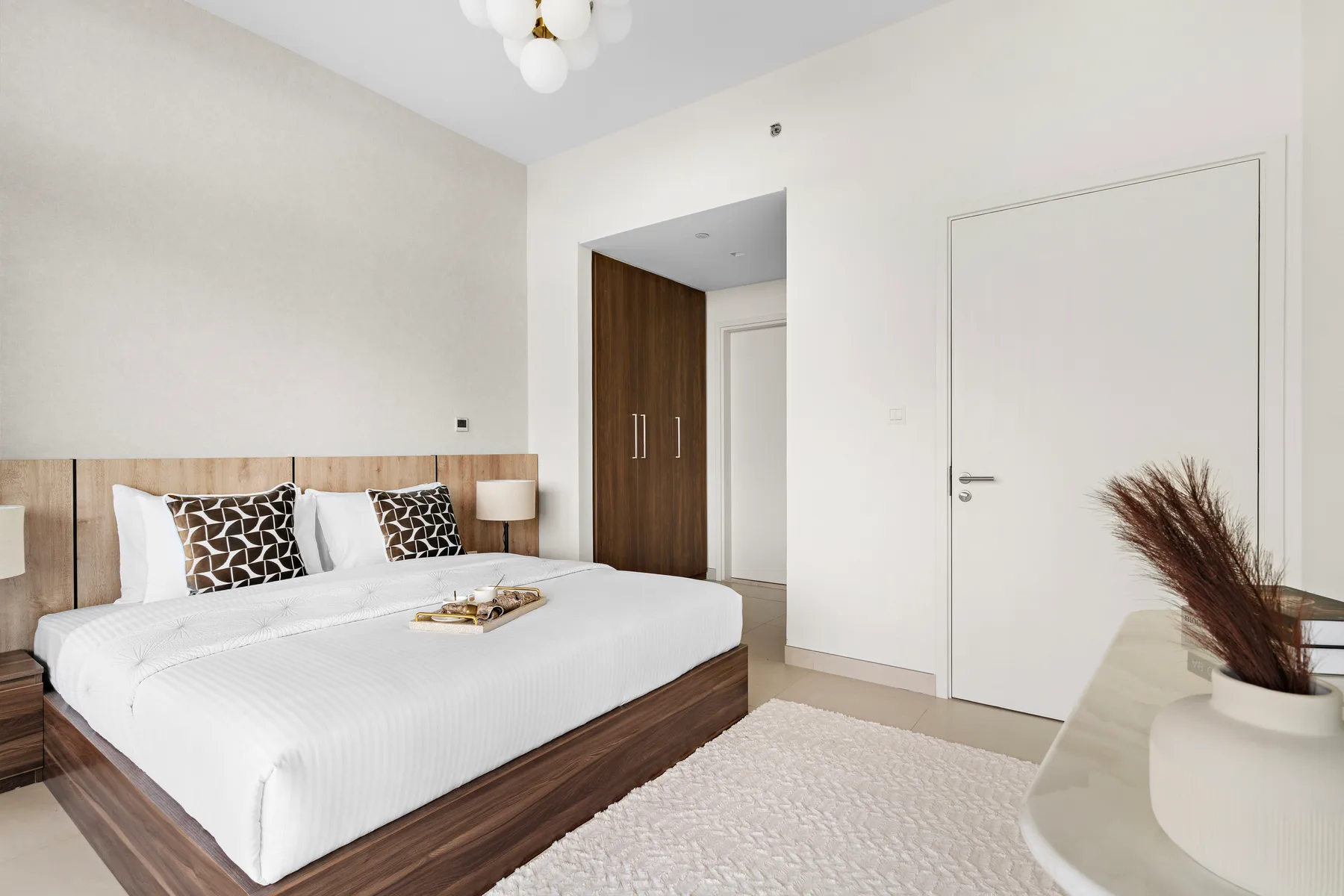 A bright bedroom with a neatly made bed and wood-paneled headboard.